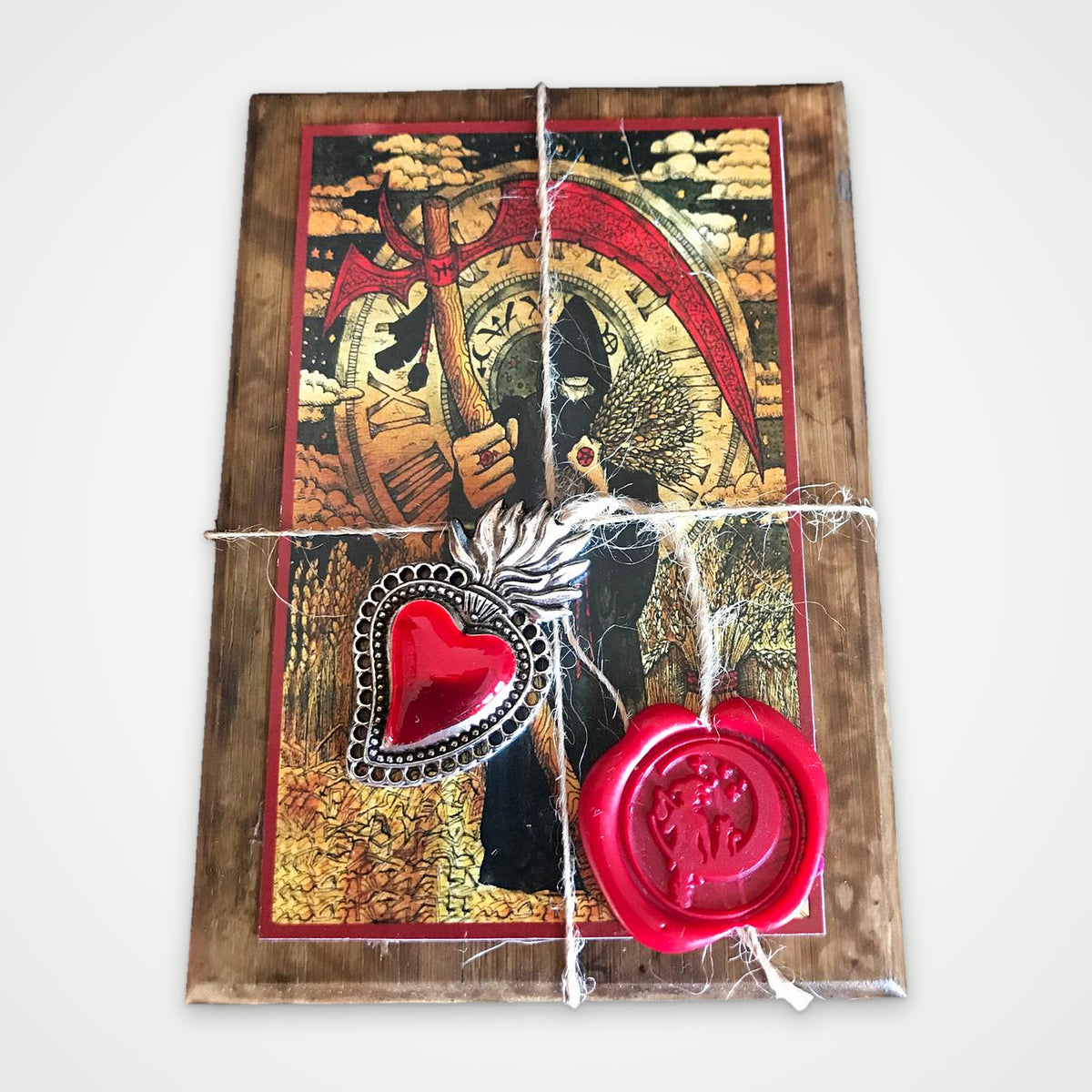 Lid of the brown wooden box with the Scythe artwork, silver heart charm and red wax seal