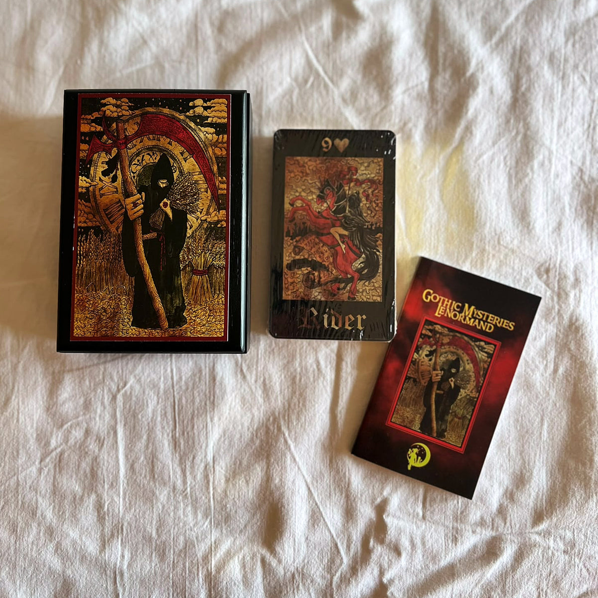 Black wooden box laid out with the 36-card deck with gilded edges and the guidebook booklet
