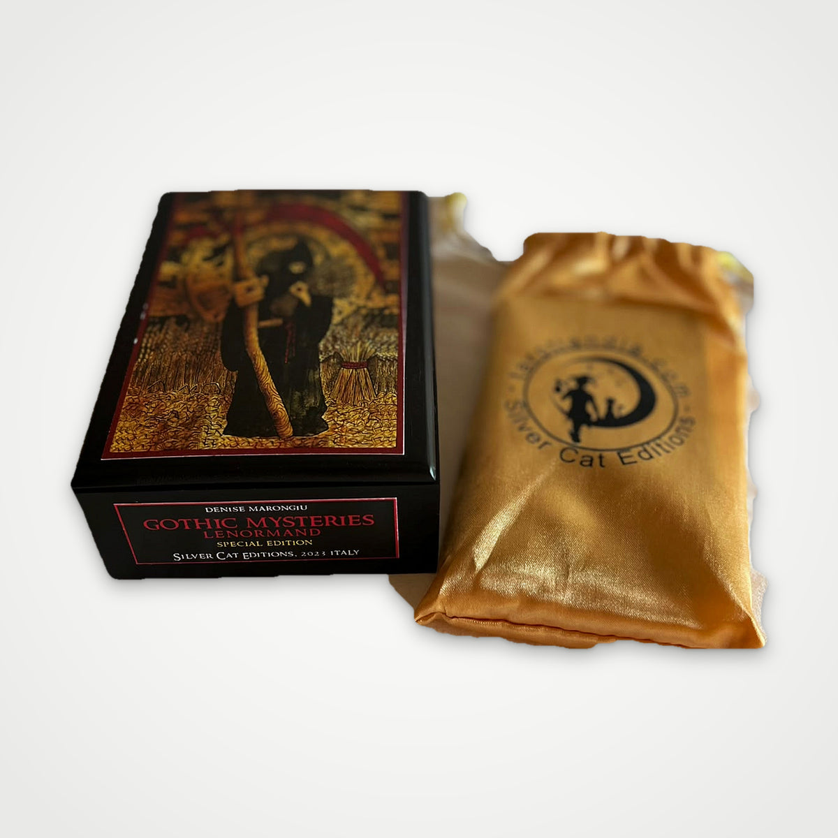 Black wooden box with edition label next to the golden Silver Cat Editions satin pouch