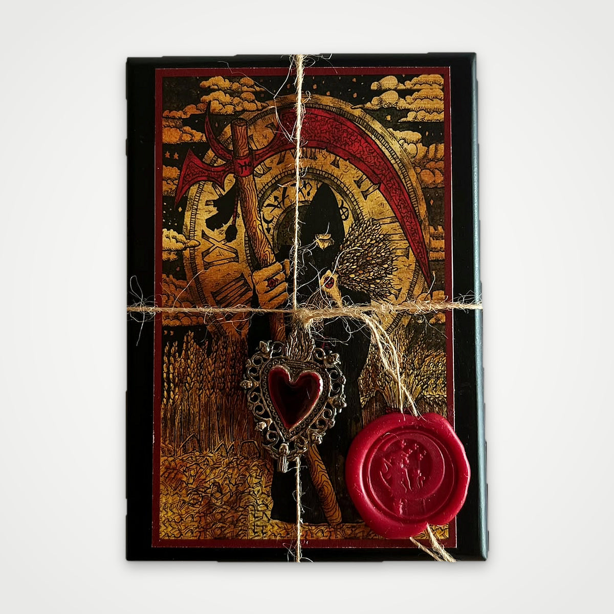 Top view of the black wooden box with the Scythe artwork, twine, red wax seal and heart charm